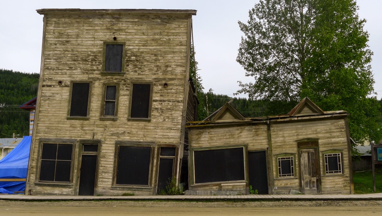 Two old wooden buildings leaning into each other on ground that has shifted as permafrost thawed, Dawson City, Yukon
